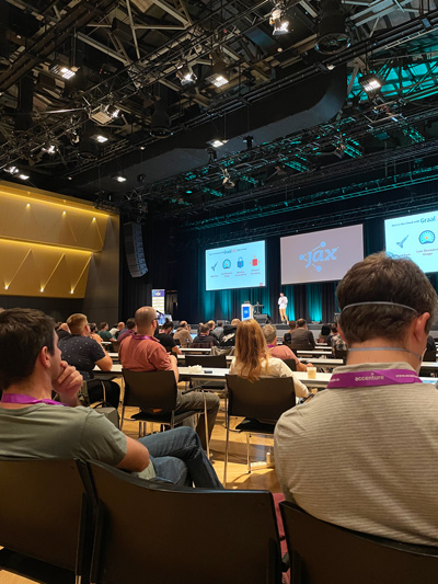 Teilnehmer bei einer Konferenz in einem modernen Veranstaltungsraum Menschen sitzen in einem großen Saal und verfolgen eine Präsentation auf der Bühne bei einer Konferenz