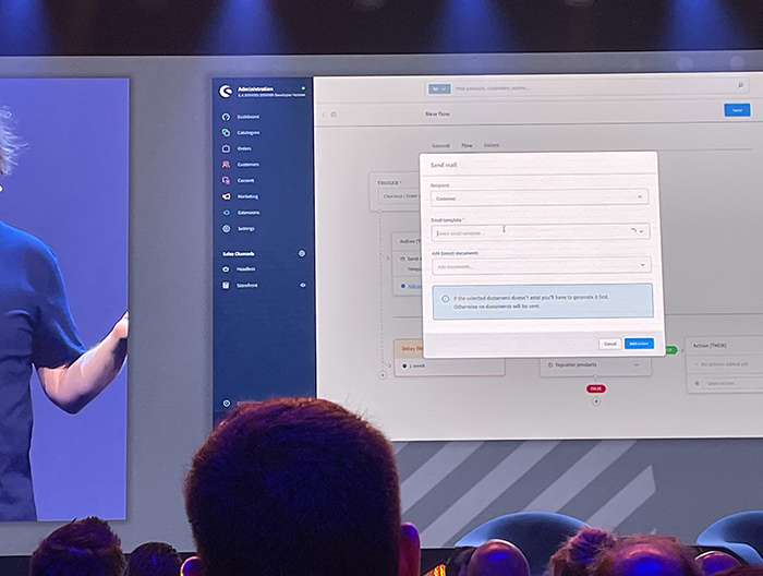 Präsentation einer Softwareplattform auf einer Konferenz Ein Bildschirm zeigt eine Präsentation der Benutzeroberfläche einer Softwareplattform während einer Konferenz. Mehrere Personen sitzen vor dem Bildschirm und beobachten die Darstellung.