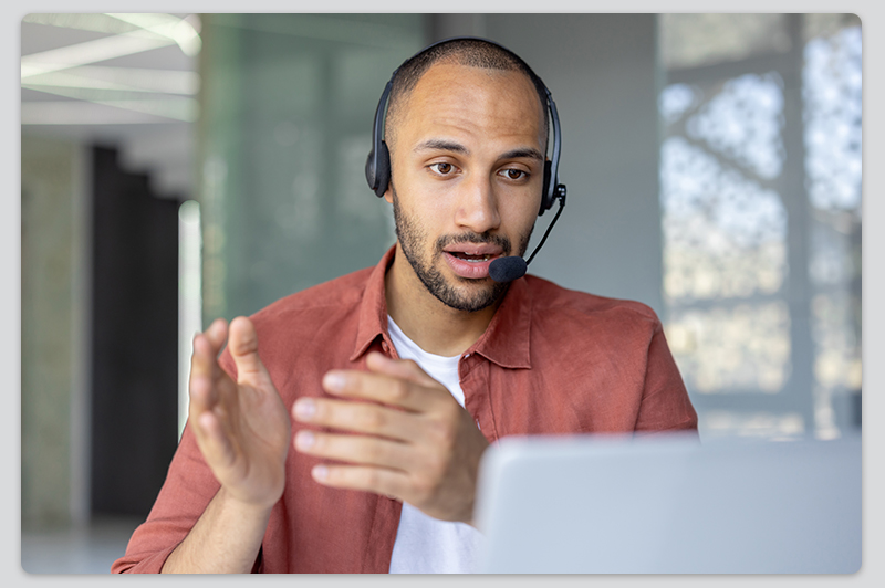 Kundensupport-Vertreter im Gespräch über Laptop mit Headset Mann mit Headset führt ein Online-Meeting am Laptop durch